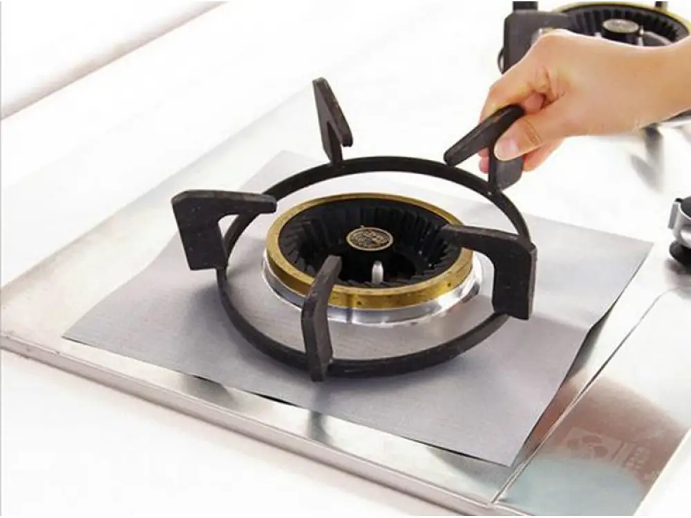 Grilles de cuisinière encrassées posées à côté d'éponges et de produits de nettoyage naturels