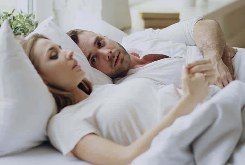 Couple allongé sur un lit, partageant un moment complice