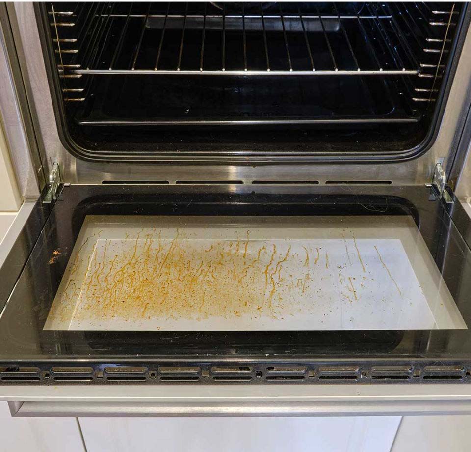 Vue rapprochée de saletés coincées entre les vitres d'une porte de four
