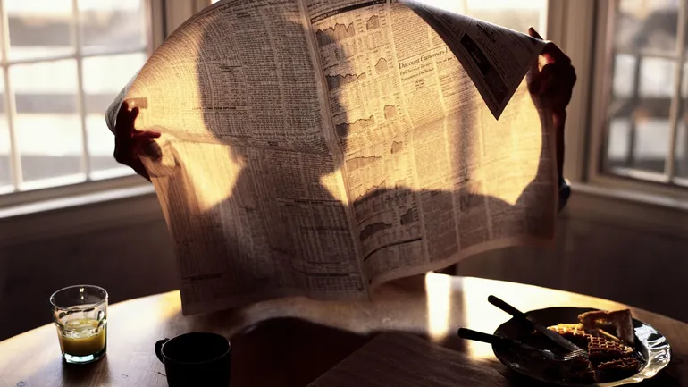 Vieille coupure de journal jaunie tenue par des mains, symbole d'un secret révélé