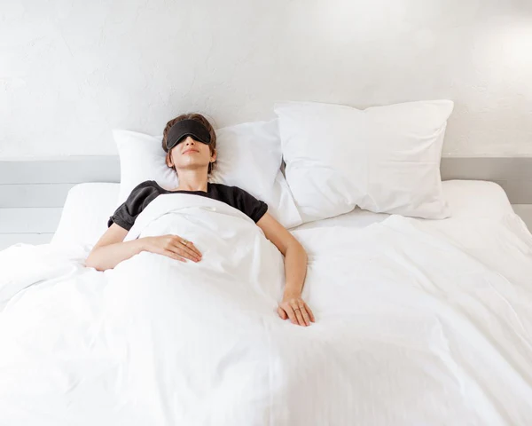 Femme souriante dormant sur le dos dans son lit