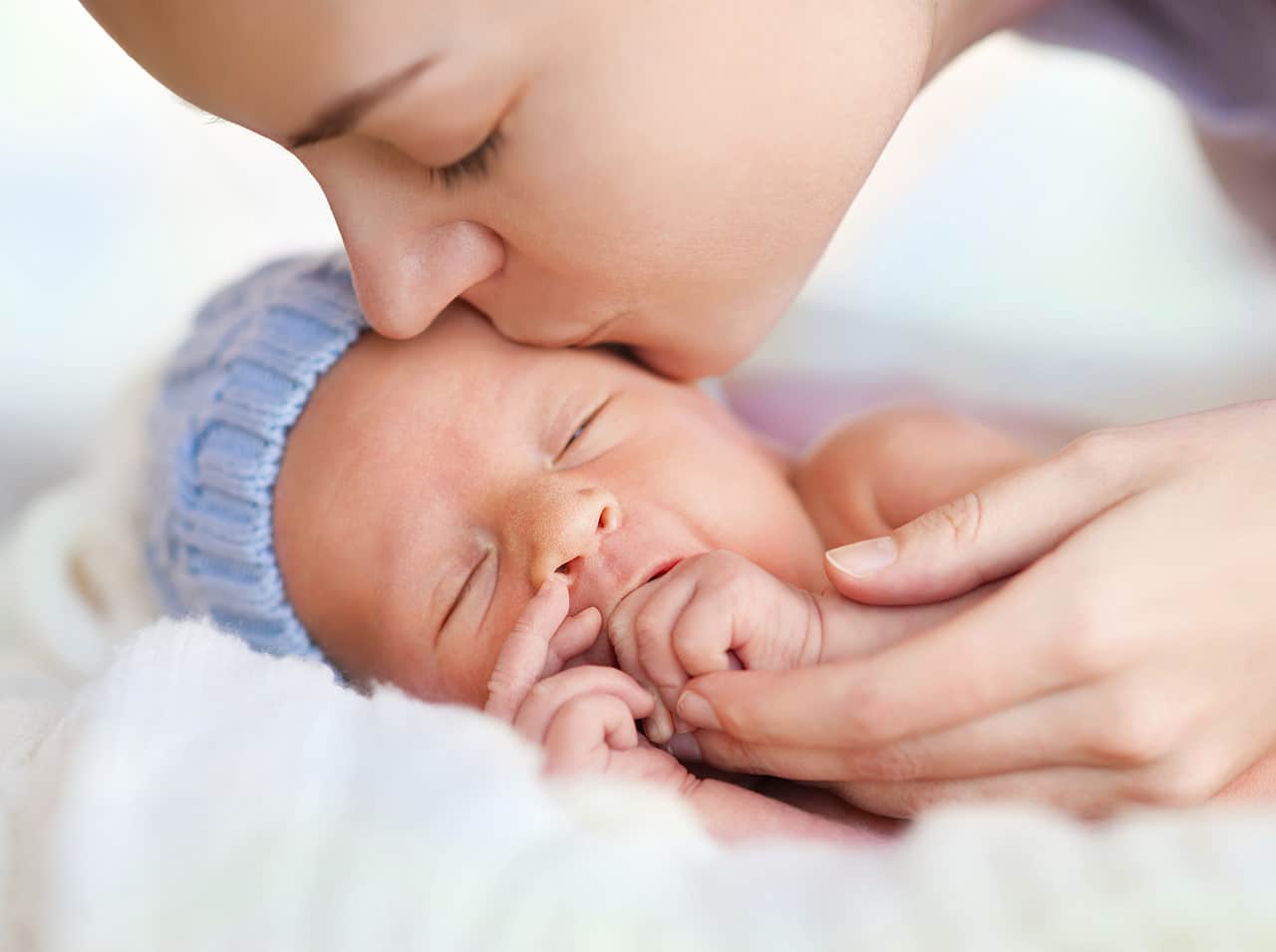 Jeune mère penchée sur le berceau de son bébé