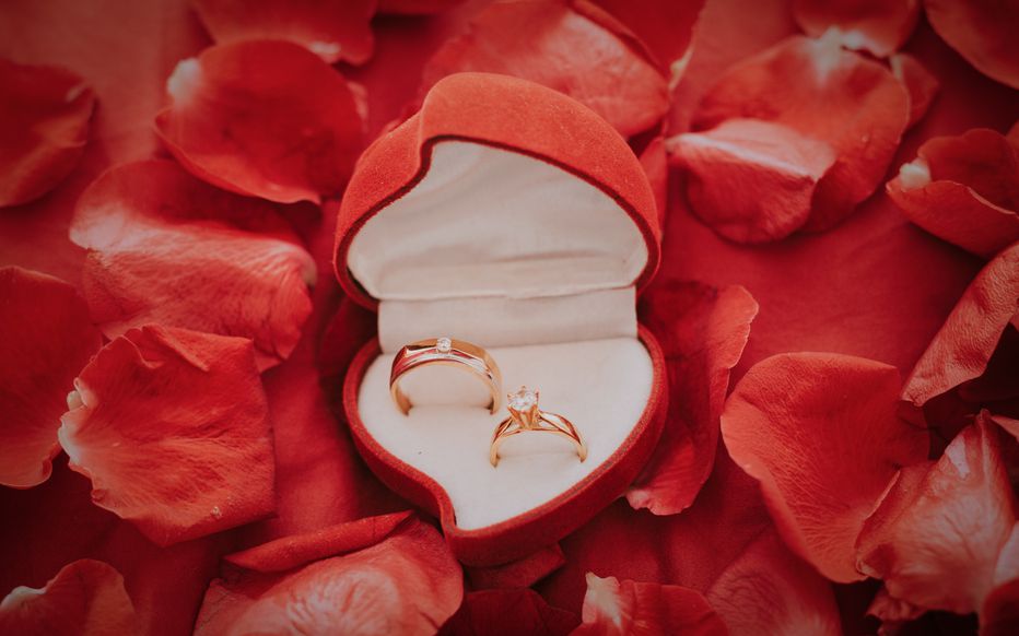 Un homme élégant s'agenouille et tend un écrin à une femme émue