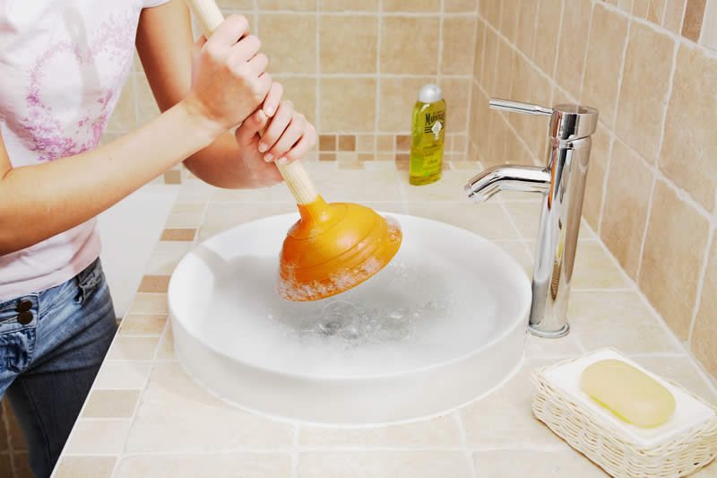 Personne utilisant une ventouse sur un évier