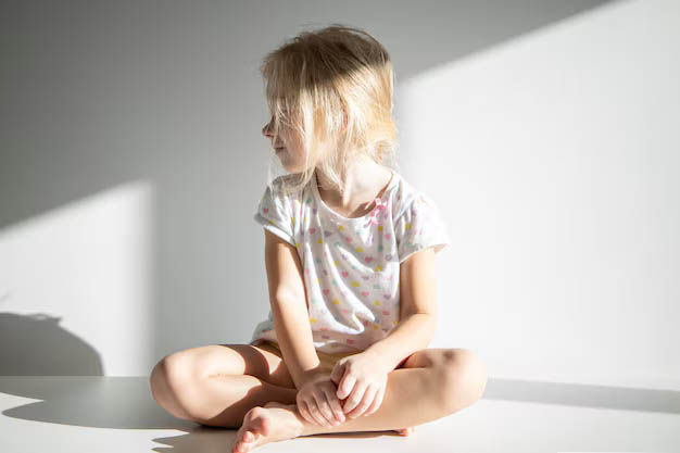 Jeune fille blonde assise, regard perdu