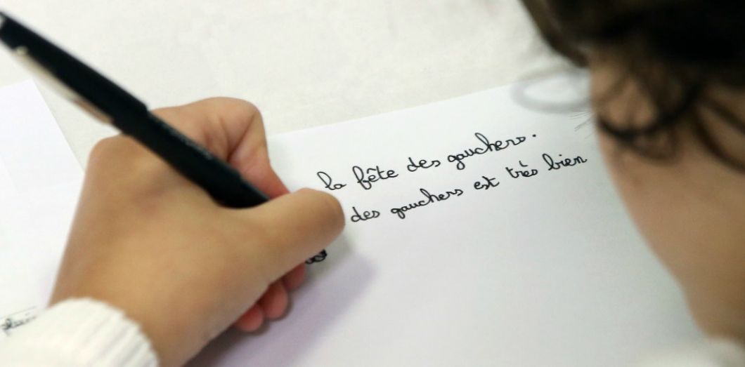 Enfant gaucher en train d'écrire, montrant la position particulière de la main