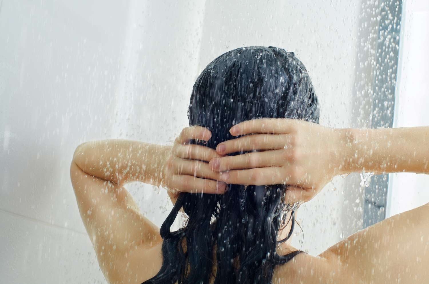 Femme se lavant les cheveux sous la douche