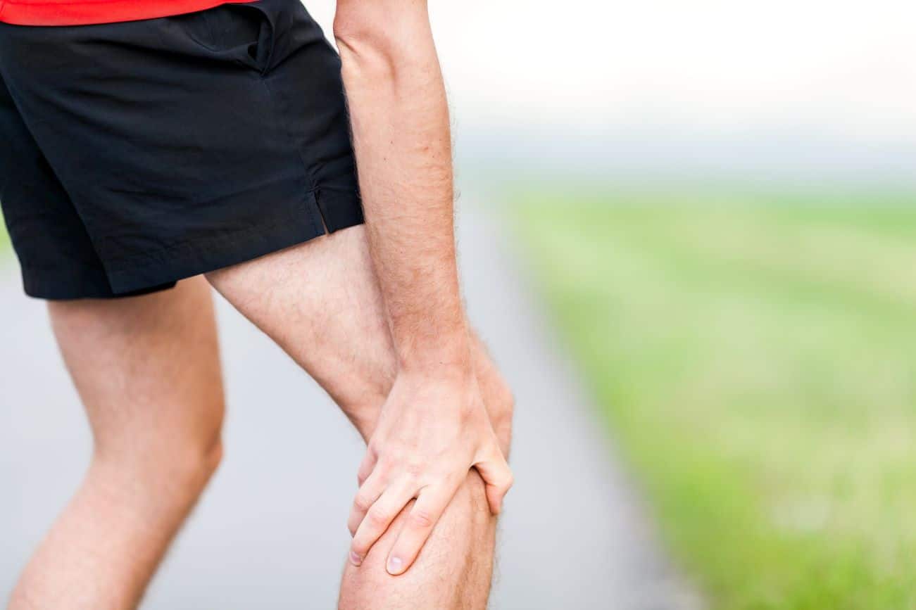 Personne massant sa jambe pour soulager une crampe musculaire
