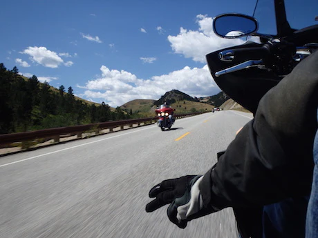 Motard faisant un signe de la main sur route sinueuse