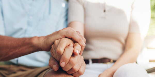 Un couple de seniors se tenant la main, l'air pensif et ému
