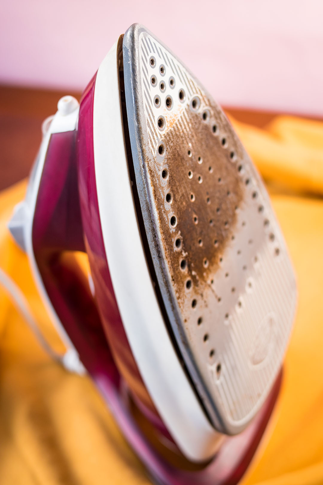 Fer &agrave; vapeur pos&eacute; sur une planche &agrave; repasser avec un tissu jaune